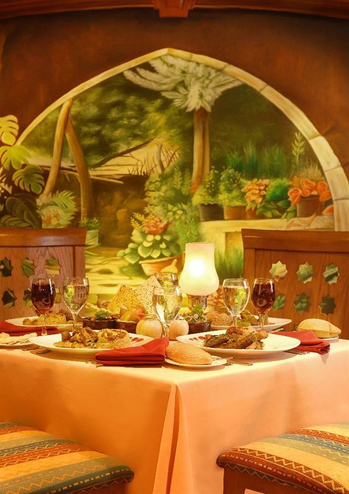 Sunrise Alex Avenue Hotel Alexandria Eksteriør bilde The photo depicts a beautifully arranged dining table set against a vibrant mural of a garden. The table features a variety of dishes, likely a mix of main courses and sides, elegantly presented on white plates. There are also several glasses, includ