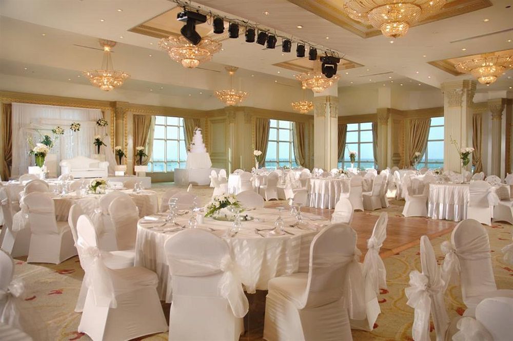 Sunrise Alex Avenue Hotel Alexandria Eksteriør bilde The photo depicts an elegant banquet hall set up for a formal event, likely a wedding or reception. The room features several round tables covered with white tablecloths and adorned with floral centerpieces. Chairs are also dressed in white covers, c