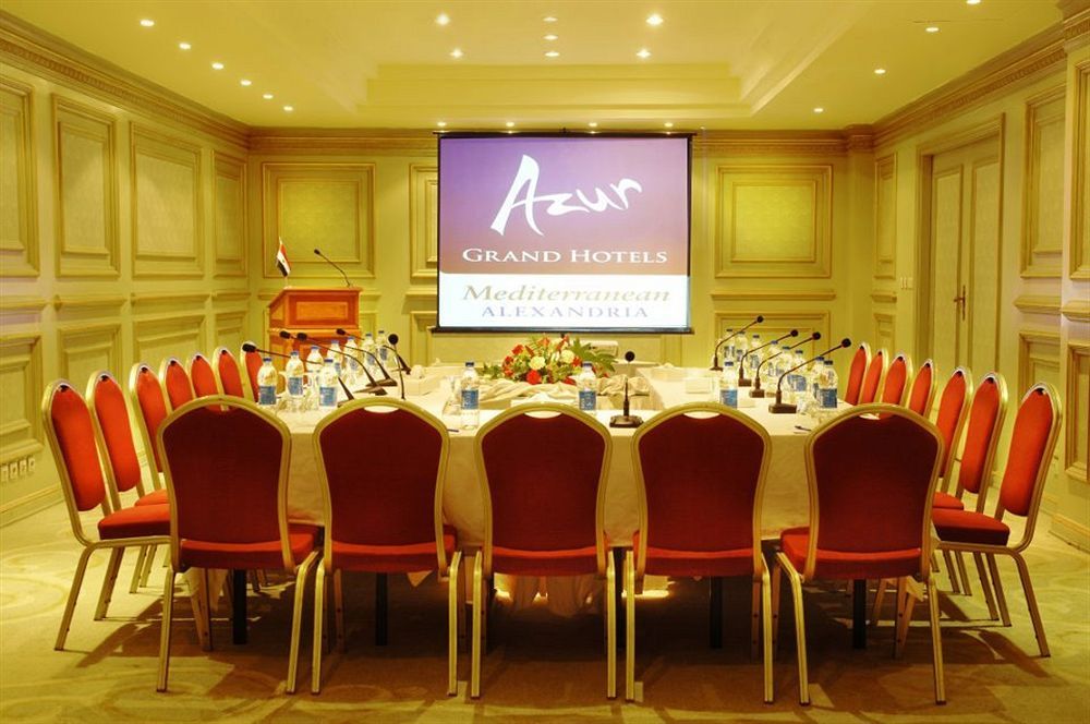 Sunrise Alex Avenue Hotel Alexandria Eksteriør bilde The photo shows a conference room set up for a meeting or event. There is a large oval table surrounded by red chairs, and the table is equipped with microphones and bottles of water. In the background, there is a projector screen displaying the logo