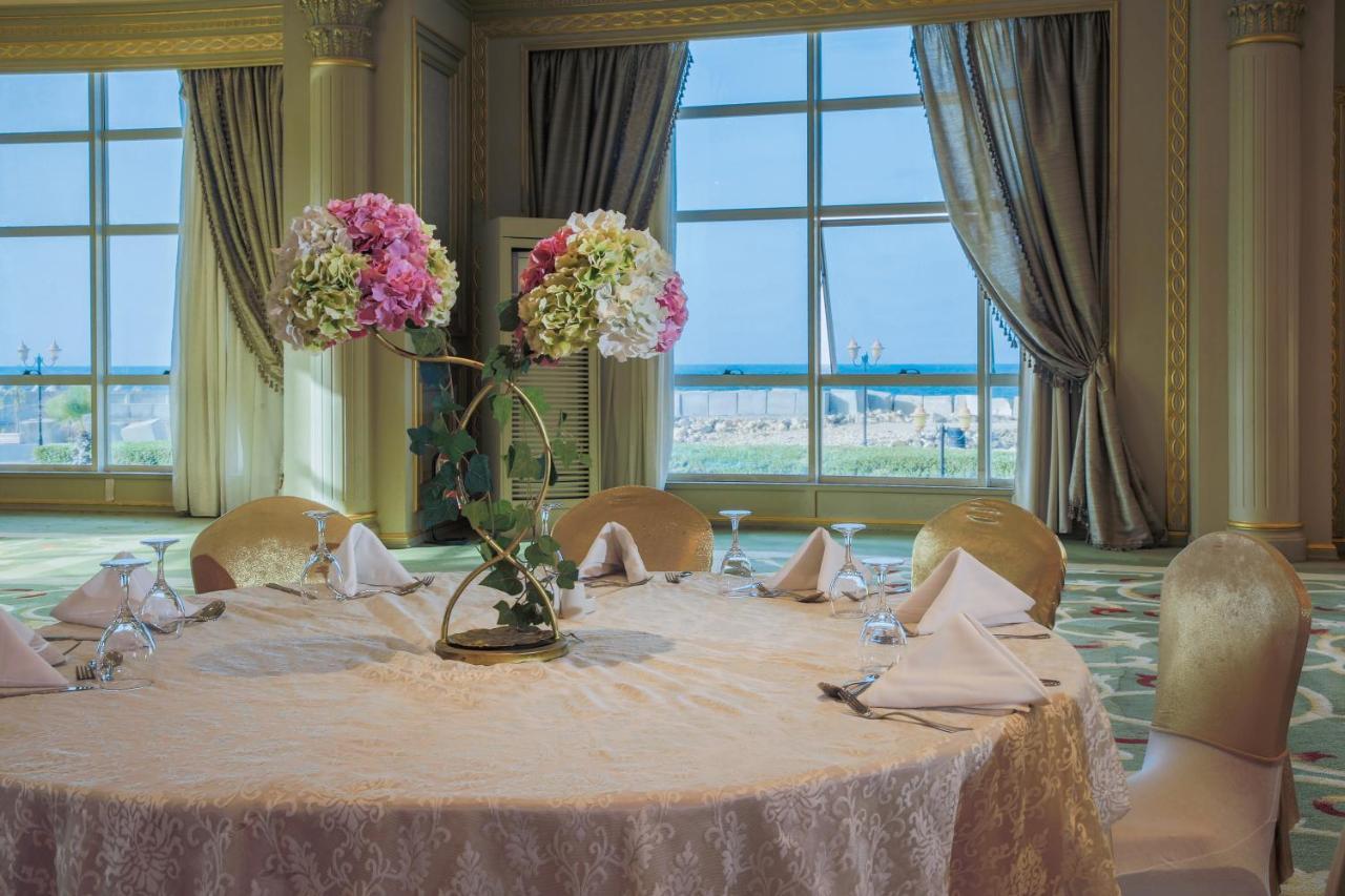 Sunrise Alex Avenue Hotel Alexandria Eksteriør bilde The photo depicts a beautifully arranged round dining table set in an elegant room. The table is covered with a light-colored lace tablecloth and features an artistic floral centerpiece with pink and white flowers. The place settings include folded n